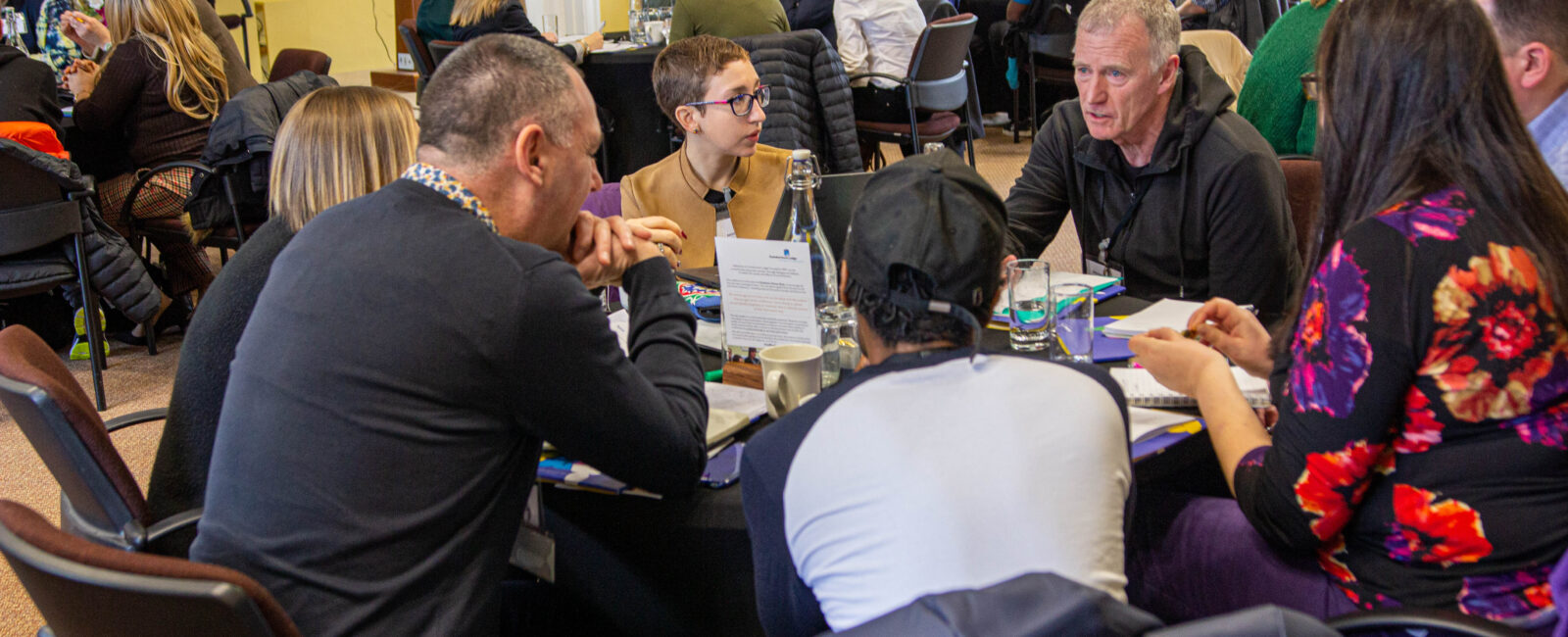 A group of people at a writing retreat sat around a table speaking
