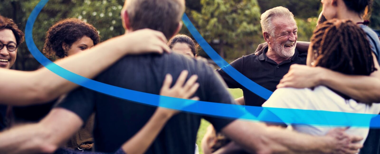 Photo of people of all ages embracing in a circle, with a blue ribbon connecting them