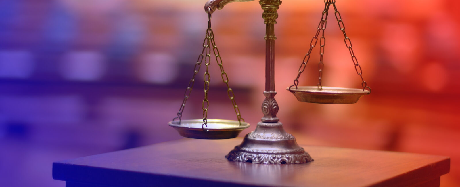 Weighing scales (scales of justice) against a blurred courtroom background