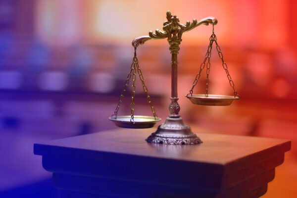 Weighing scales (scales of justice) against a blurred courtroom background