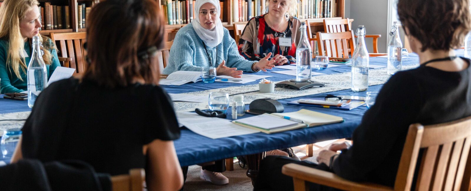 Conference delegates sat around a table in the library engaged in a discussion.