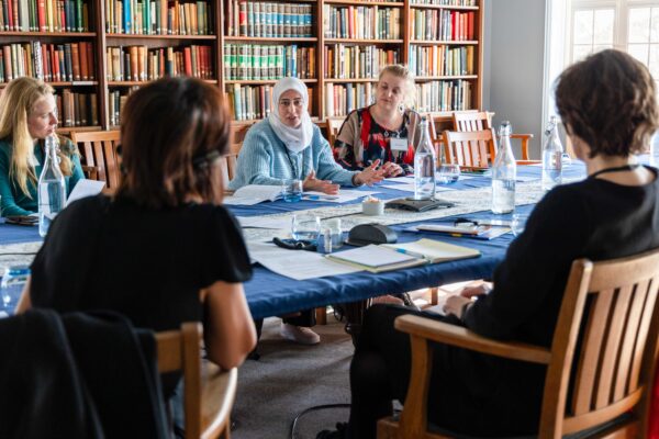 Conference delegates sat around a table in the library engaged in a discussion.