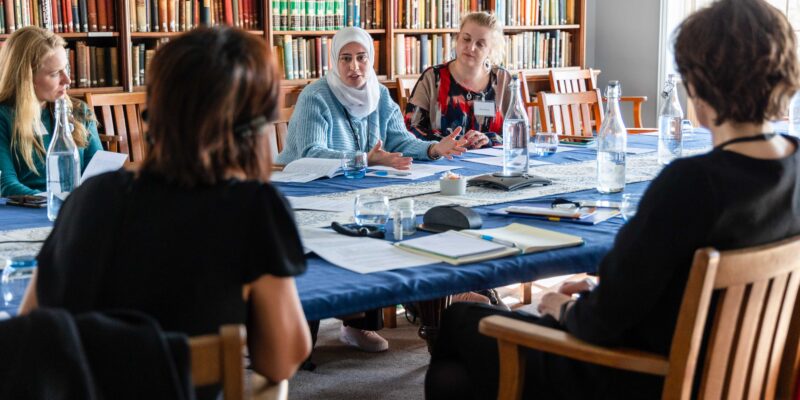 Conference delegates sat around a table in the library engaged in a discussion.