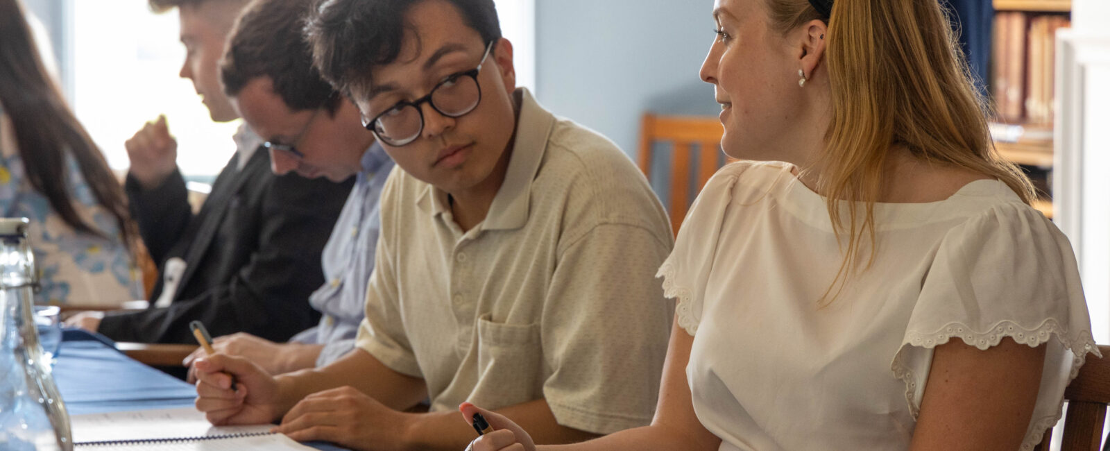 People sitting at a table talking and taking notes during a meeting