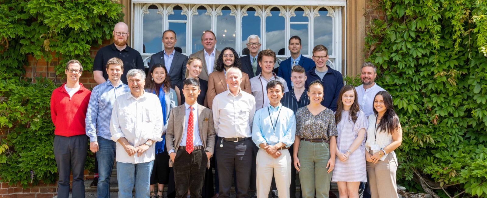 A group of participants in the seminar standing outside the Tapestry Hall door of Cumberland Lodge.