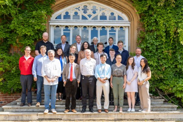 A group of participants in the seminar standing outside the Tapestry Hall door of Cumberland Lodge.