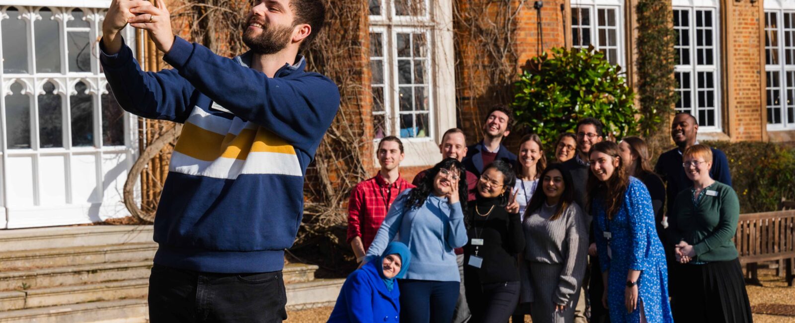 A group of Fellows takes a selfie outside Cumberland Lodge.