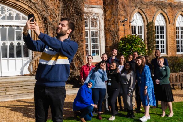 A group of Fellows takes a selfie outside Cumberland Lodge.