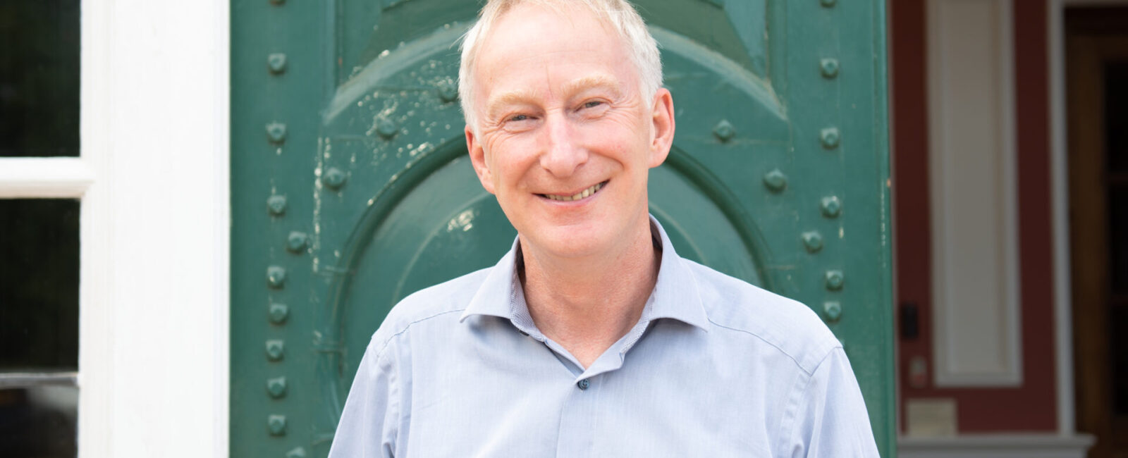 Chief Executive Dr Ed Newell standing in front of a green door