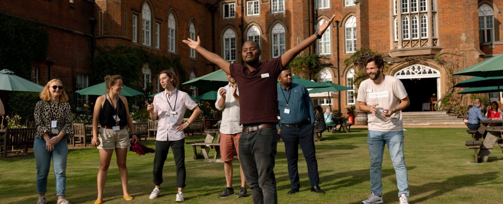 A group of Fellows playing croquet on the lawn outside the Lodge. One has his arms in the air, celebrating.