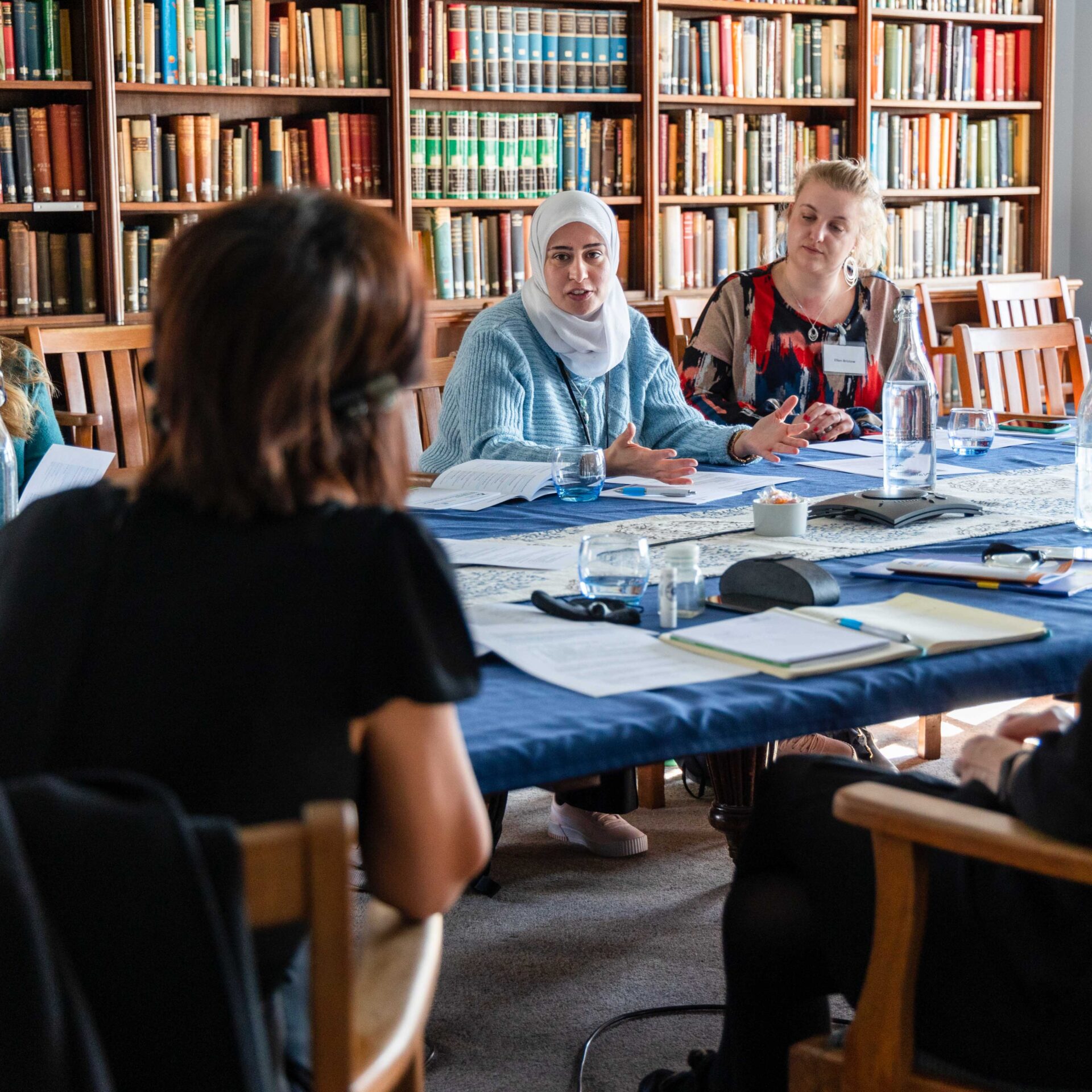 A group of Fellows taking part in a discussion seated around a table in the library