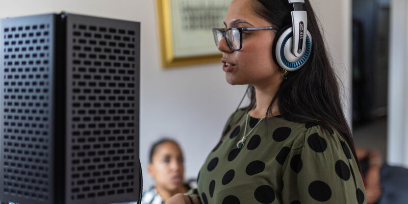 Student with headphones on next to speaker